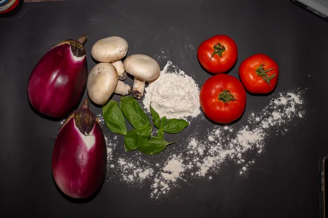 Melanzane, funghi, pomodori e basilico sul banco di lavoro