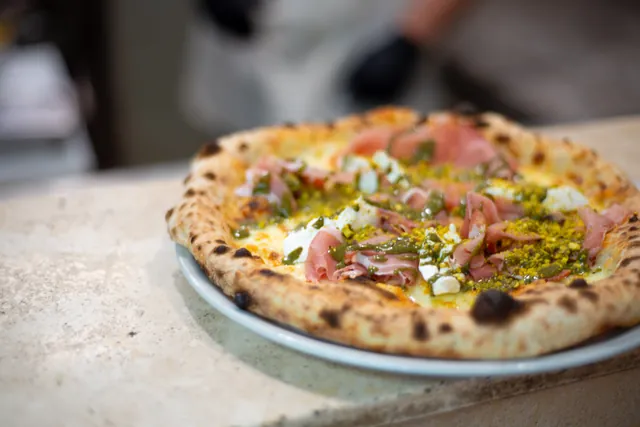 Pizza appena sfornata con crudo, burrata e granella di pistacchio