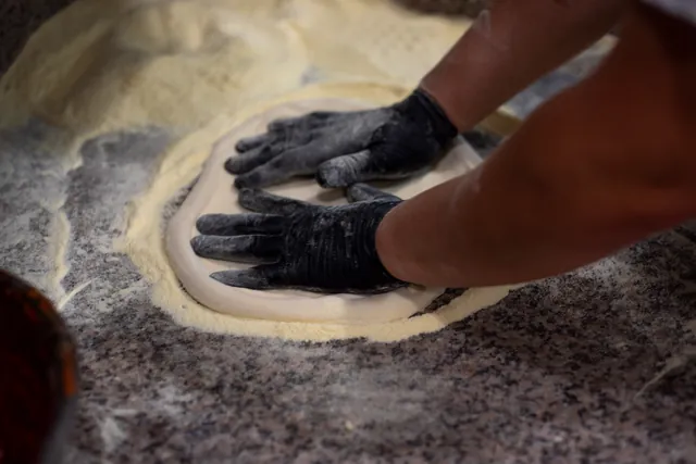 Il pizzaiolo stende un disco di impasto sul marmo infarinato